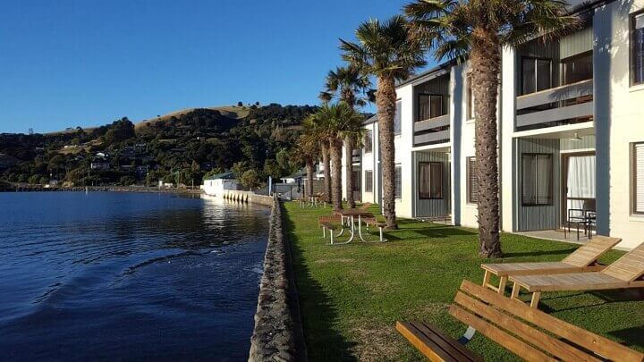 The waterfront area with sun loungers and other outdoor furniture at Akaroa Waterfront Motels