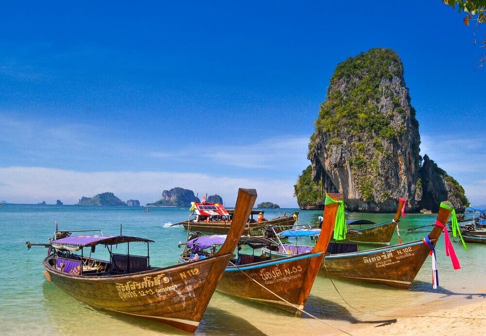 Why is Thailand So Cheap Hero Image - traditional longtail boats amongst a stunning natural scenery