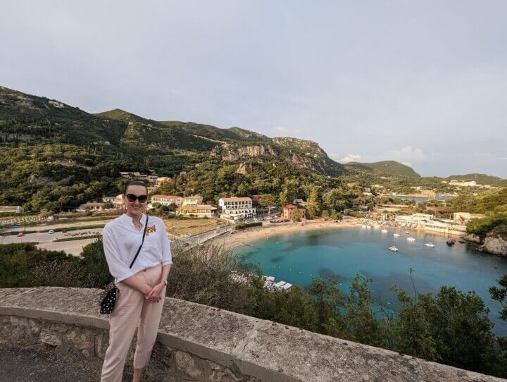 Ksenia standing on a hill in Corfu's Paleokastritsa with the main beach, Agios Spiridon behind her.