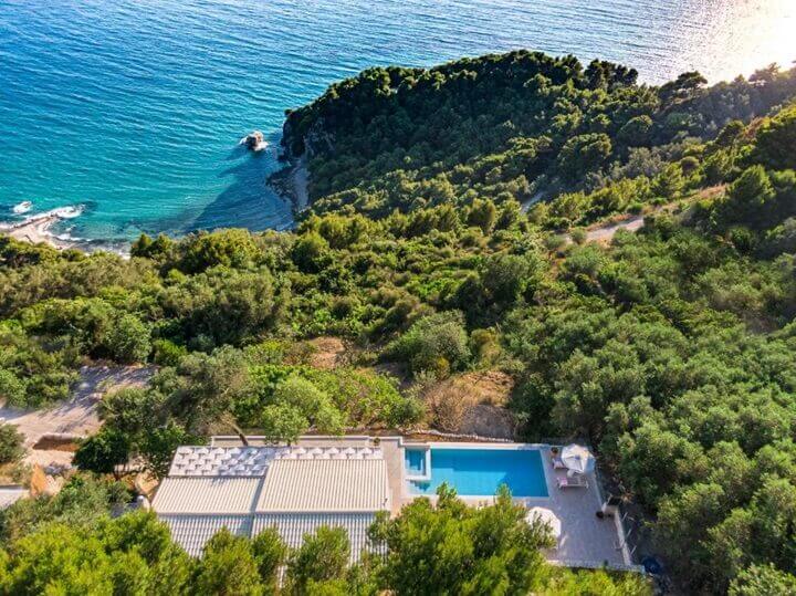A bird's eye view of the Ocean View Luxury Villa and its private pool, set on a spectacular coastal hillside